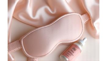 Luxury silk sleep mask and a natural herbal supplement bottle.