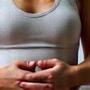 Close up of hands over abdomen demonstrating deep breathing exercise, focus on serene gesture.